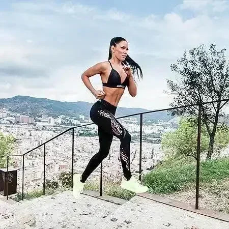 Sportlich gekleidete Frau joggt draußen auf einer Treppe mit Stadtblick im Hintergrund.
