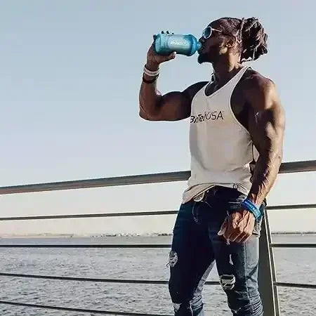 Muskelbepackter Mann im BiotechUSA-Tanktop trinkt Proteinshake am Wasser, Fitness, Supplement