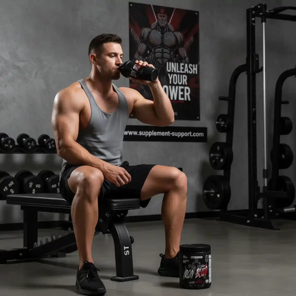 Sportler im Fitnessstudio trinkt Trainingsbooster, Iron Blood Dose auf dem Boden, Hanteln im Hintergrund