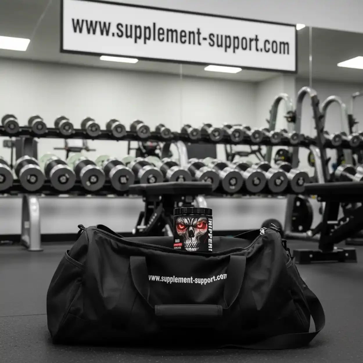 Sporttasche mit Pre-Workout Booster vor Hanteln im Fitnessstudio, Trainingszubehör